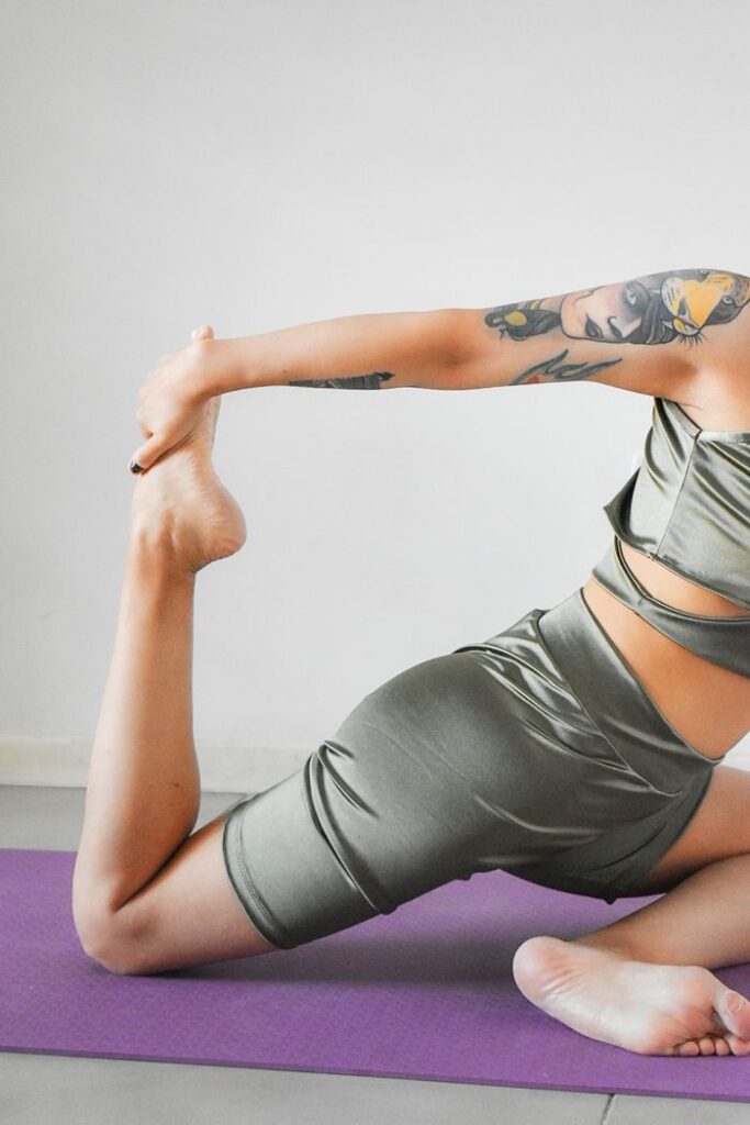Female athlete in sportswear practicing a stretching pose on a yoga mat.
