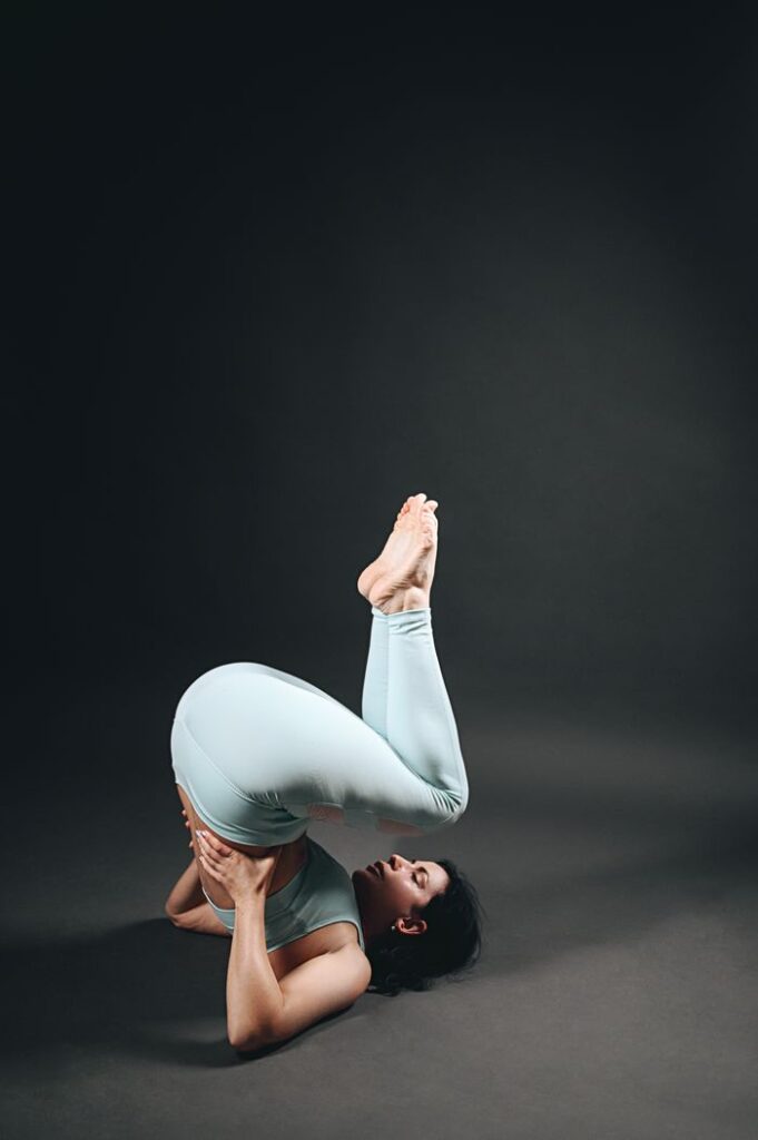 Woman performing challenging yoga pose showing strength and flexibility in an indoor studio setup.