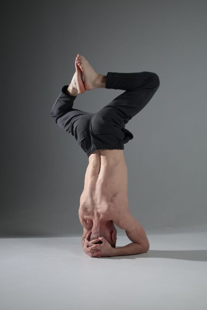 A man performing a headstand yoga pose in a minimalistic studio setting.