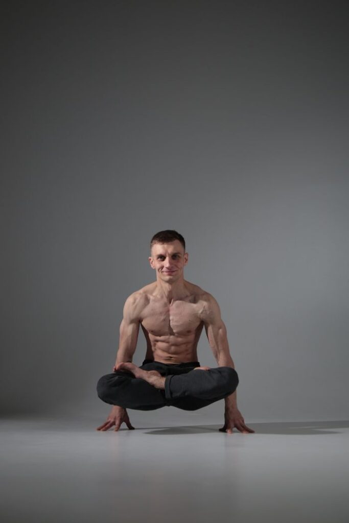 Muscular man performing a yoga pose on a studio floor, showcasing strength and balance.