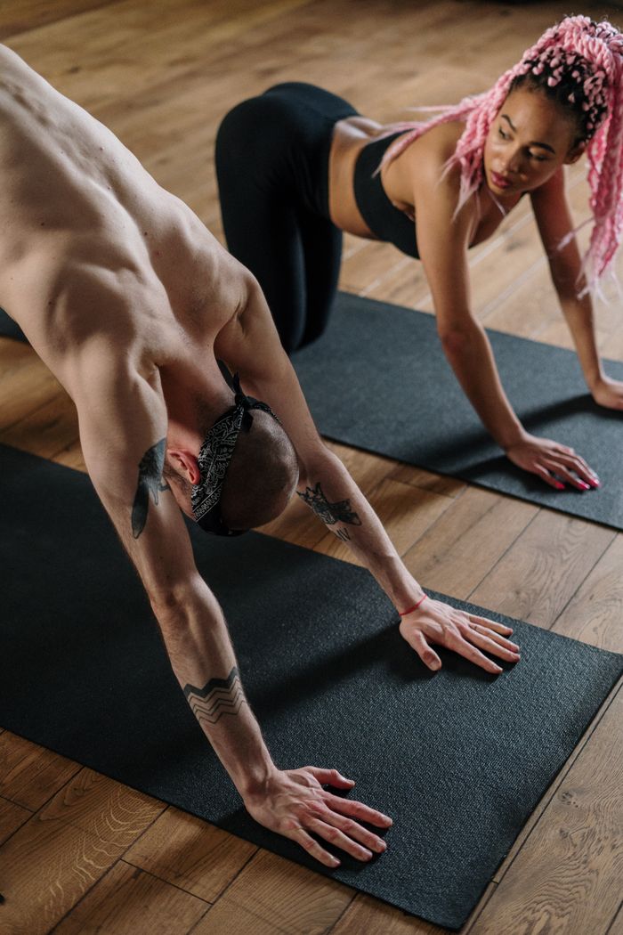 A diverse pair practicing yoga indoors, emphasizing fitness and wellbeing.